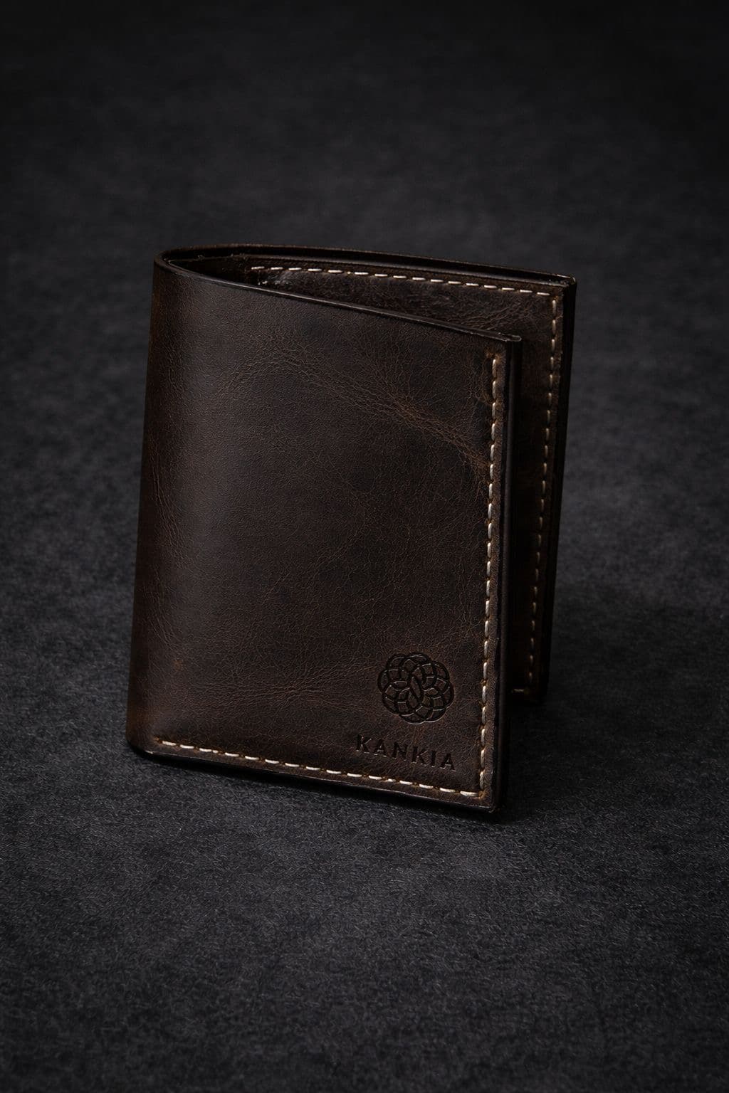Kankia dark brown full-grain bifold wallet, closed — Kankia logo embossed, dark studio background