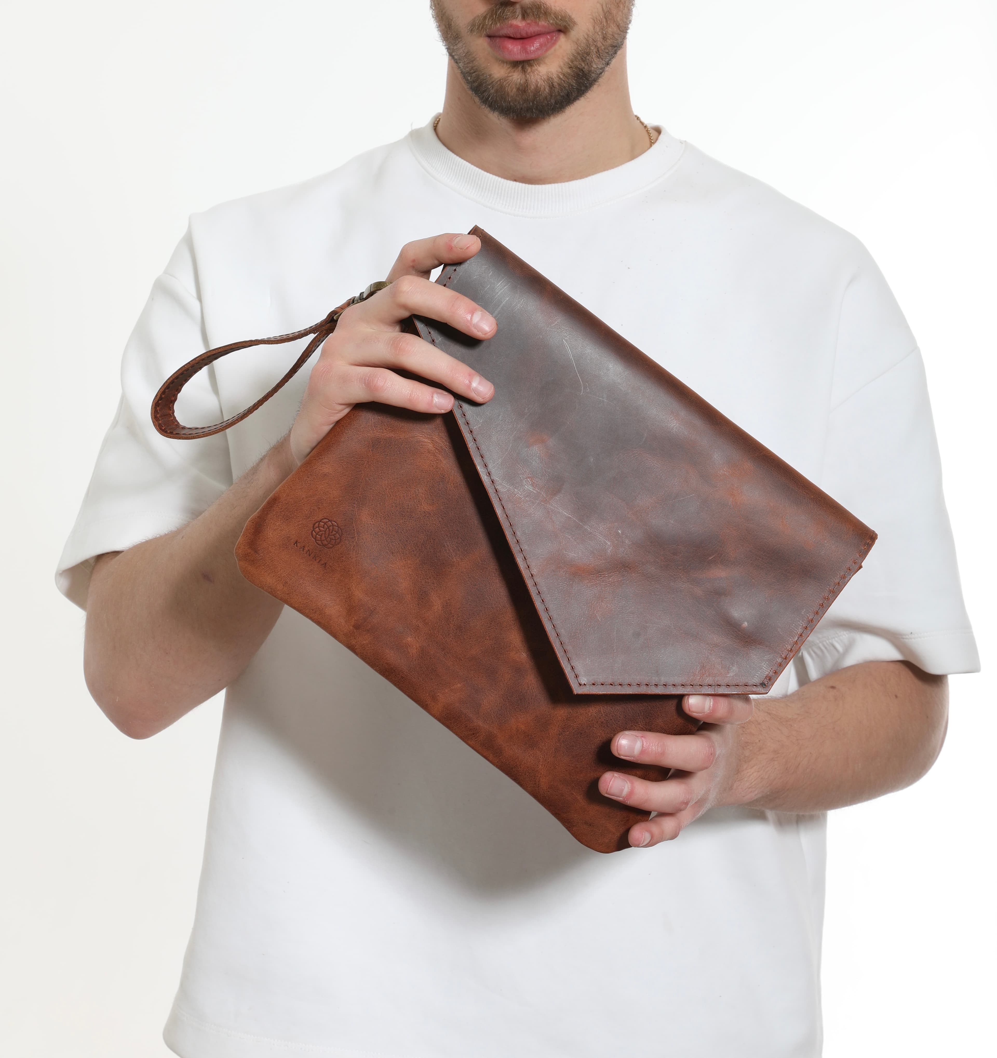 Model holding a two-tone brown leather envelope clutch handcrafted by Kankia