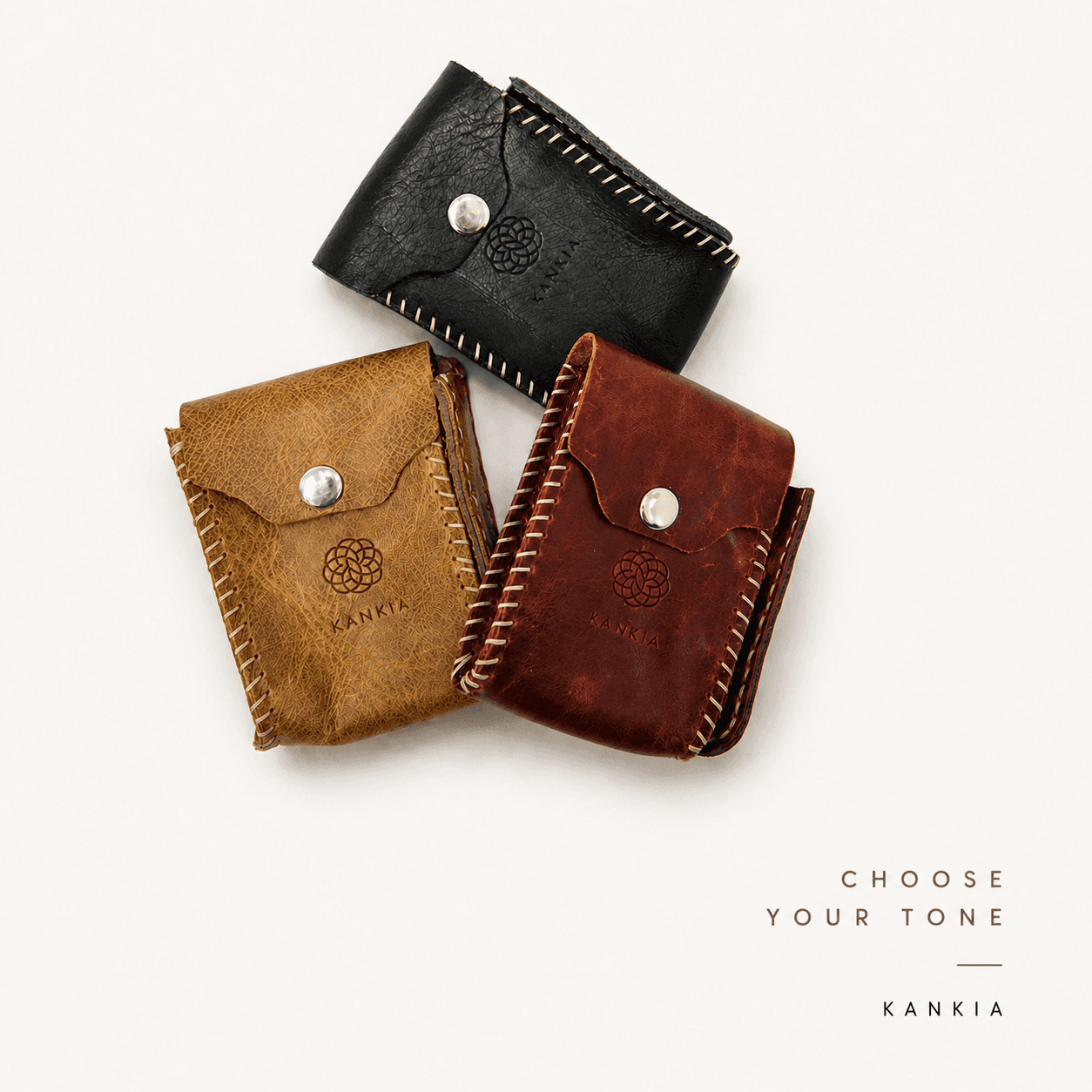 Kankia leather card wallets flat lay — black, tan and burgundy on white background